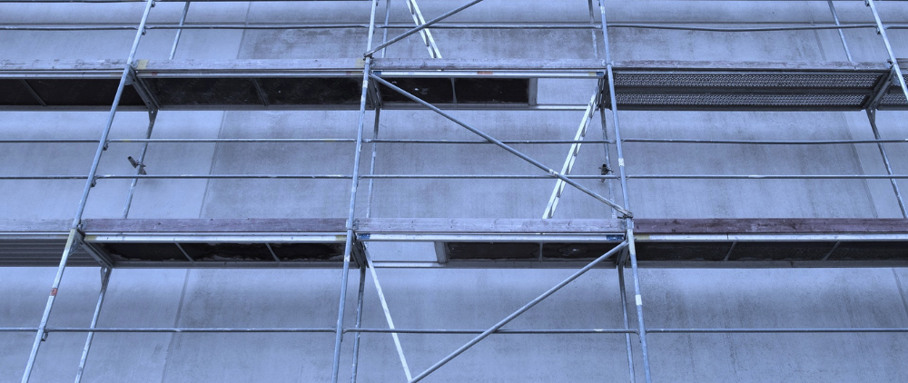 Gerüst an einer grauen Betonwand – Sinnbild für strukturelle Neuaufstellung